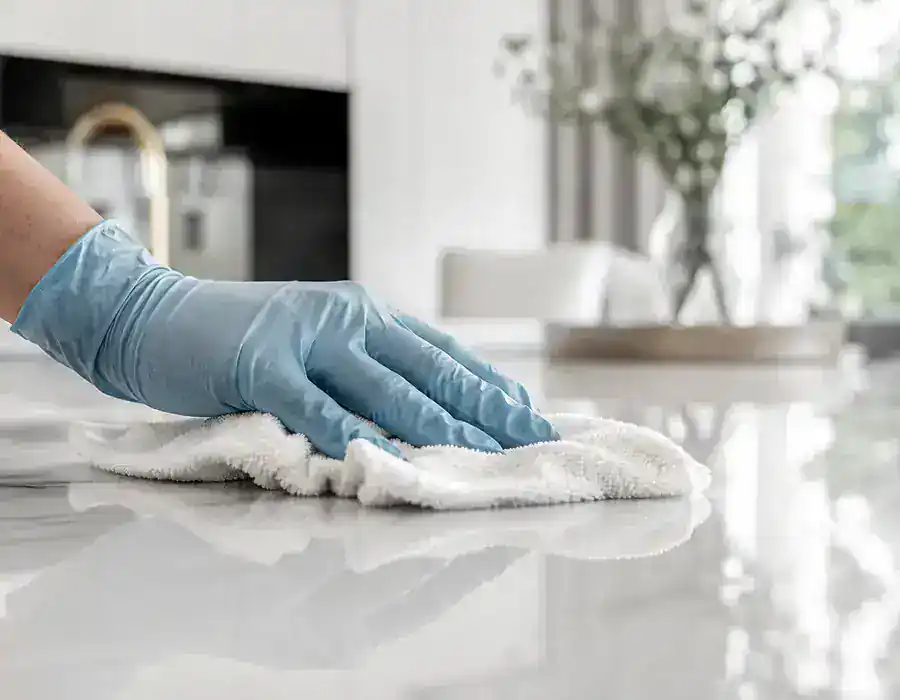 Mano enguantada limpiando una superficie clara